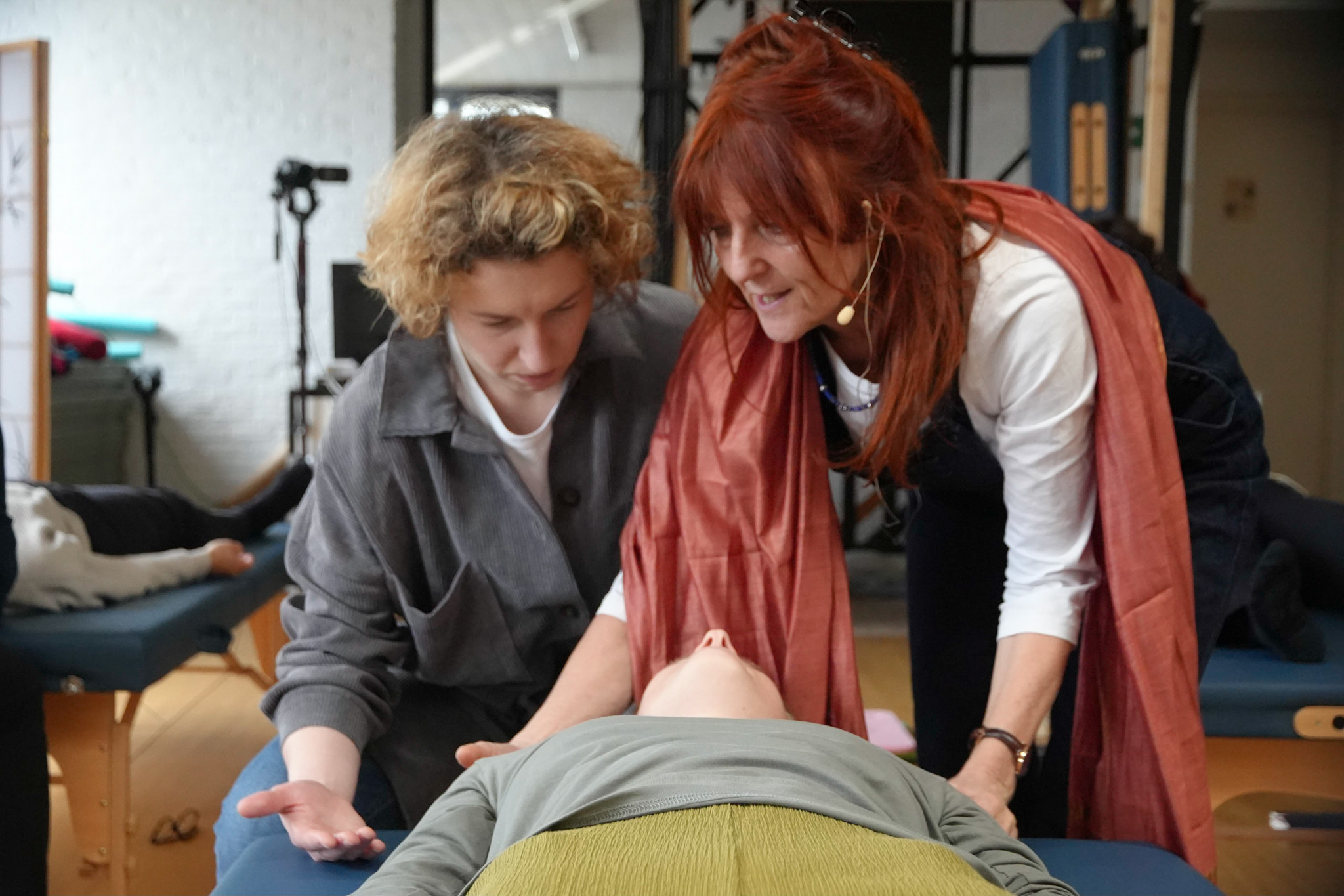 Pia Appelquist montre un travail par le toucher auprès d’une participante, sous le regard d’une élève.